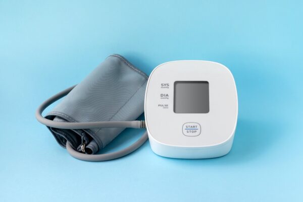 Automatic blood pressure monitor on blue background. Medical electronic tonometer